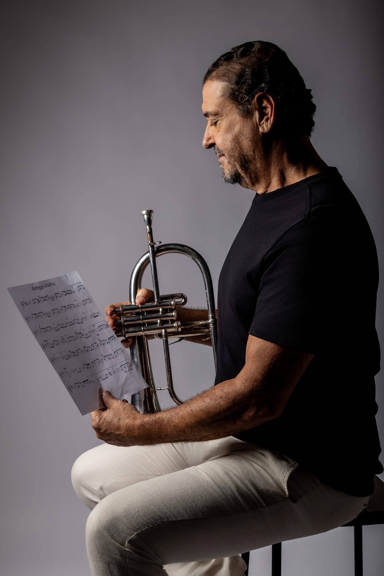 Silvério Pontes seated, reading a score with the flugelhorn on his lap