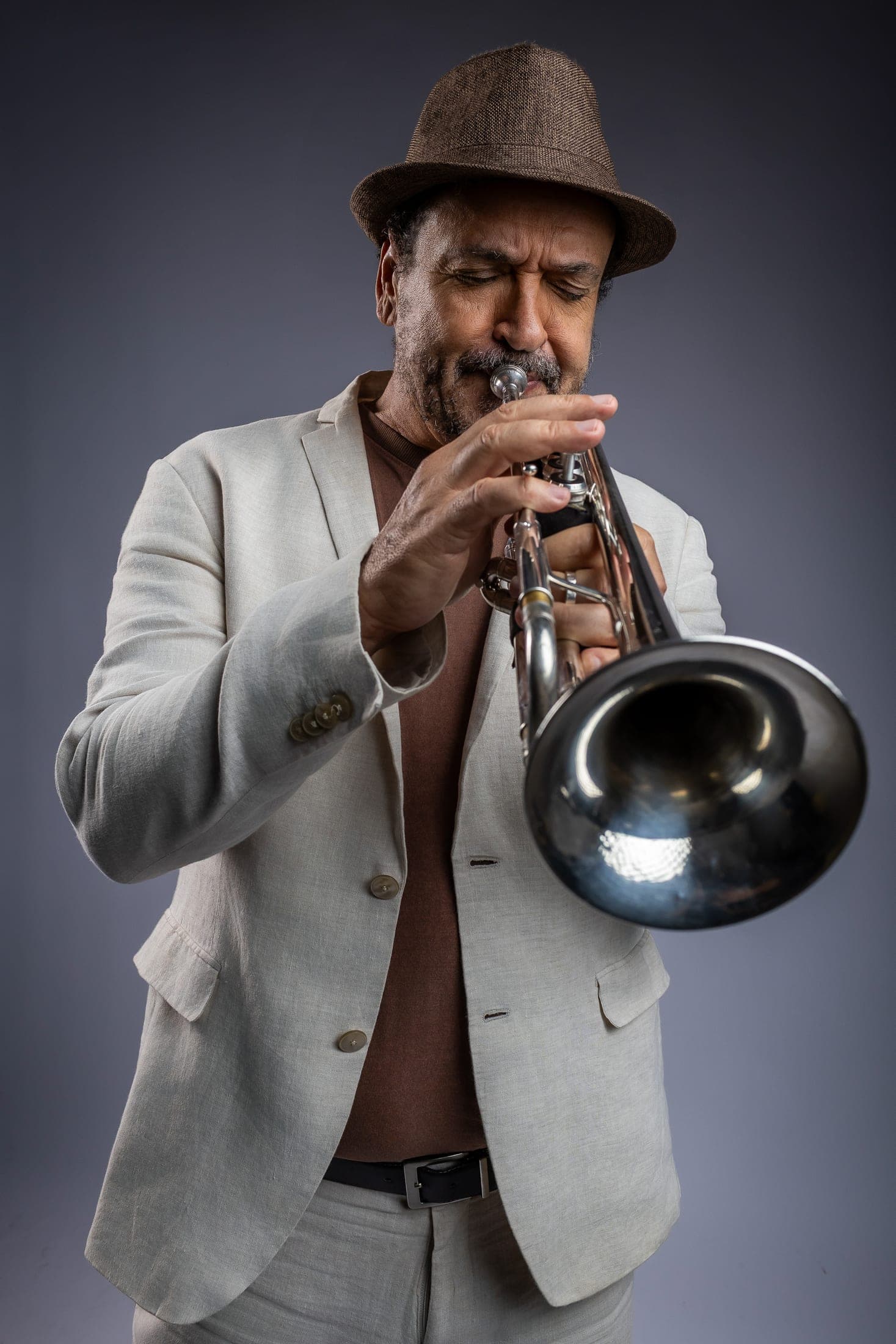 Silvério Pontes in a light linen suit and hat, playing the trumpet head-on